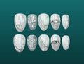 Ten press-on nails in a bridal design with white lace florals, silvery satin drapery, and engagement ring flourishes on a shining white silver base. 