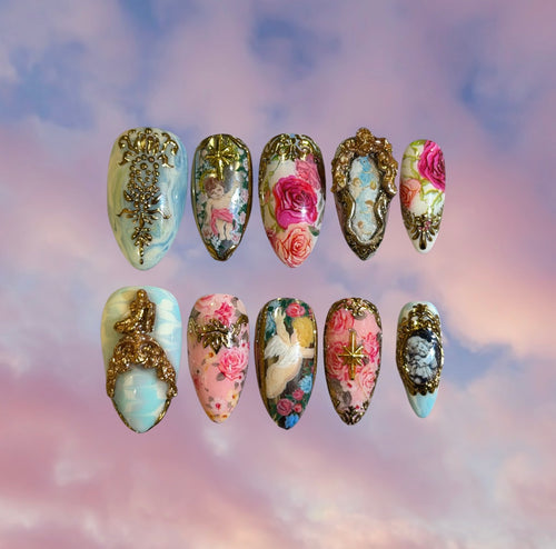 Luxury press-on nail set with Rococo style vintage floral and cupid designs on pink and blue background.