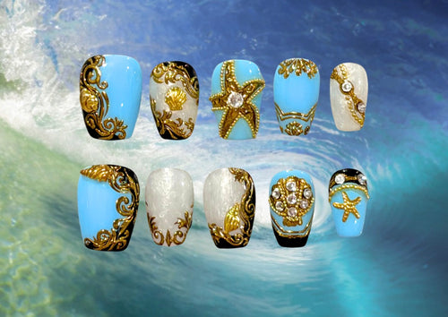 Ten press-on nails featuring golden marine motifs in baroque style on a glossy blue, black, and pearlescent base with crystal accents. 