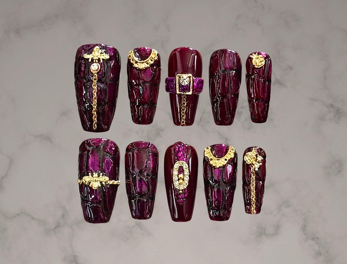 Luxury aubergine purple crocodile texture press-on nails with gold chains, buckles, clasps, and dimensional hardware