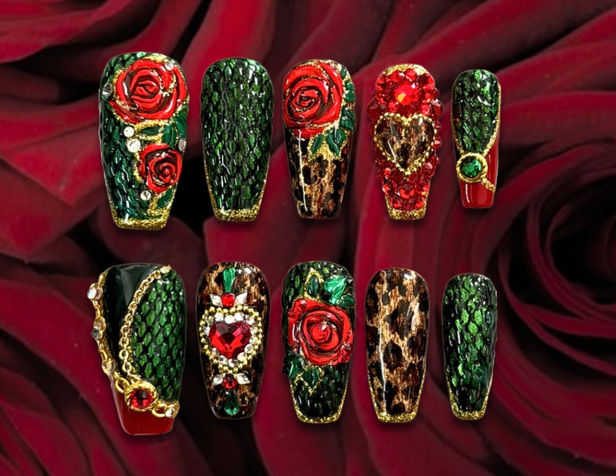 Luxury emerald green snakeskin and leopard print press-on nails with red roses, gold chains, heart-shaped gemstones, and jeweled accents.
