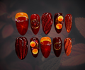 Luxury press-on nails featuring hyperrealistic design of citrus fruit in mulled wine or sangria