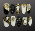 Luxury press-on nails featuring white marbling, cameo and black quilted cushion sculptural designs with gold and pearl accents